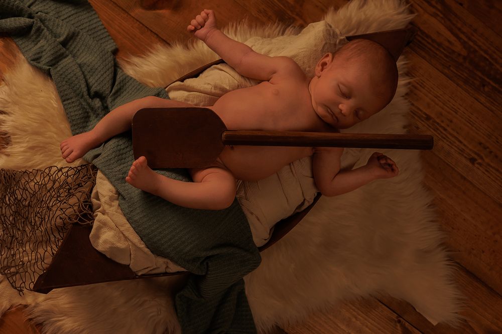 Peaceful newborn resting on rustic wooden surface with white textured fabric.