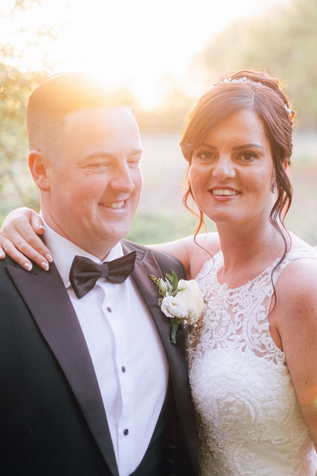 A wedding couple shares an intimate moment during golden hour, with sunlight creating a romantic glow around them.
