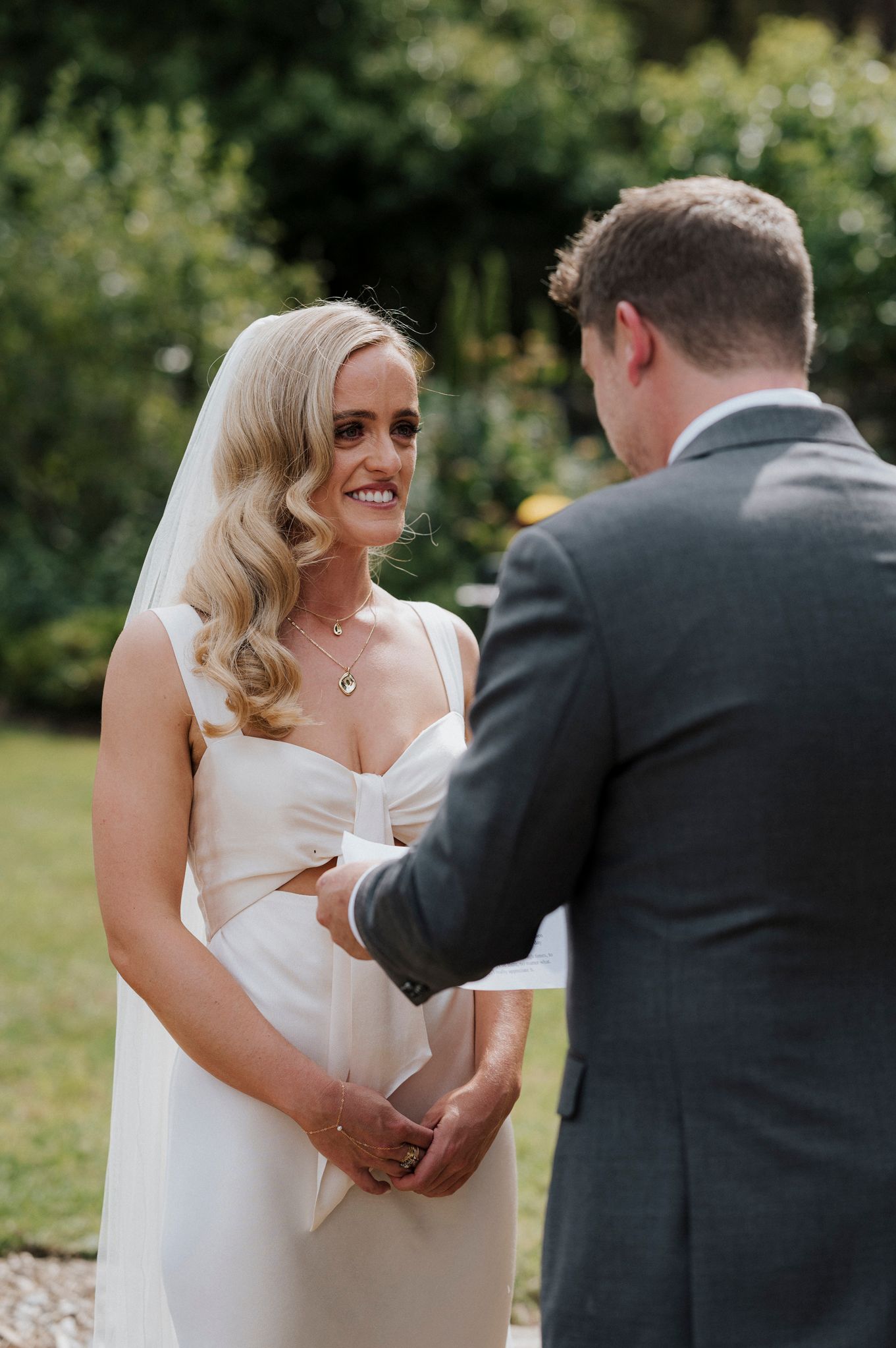 Tender moment between couple during outdoor wedding ceremony as they exchange vows and rings.