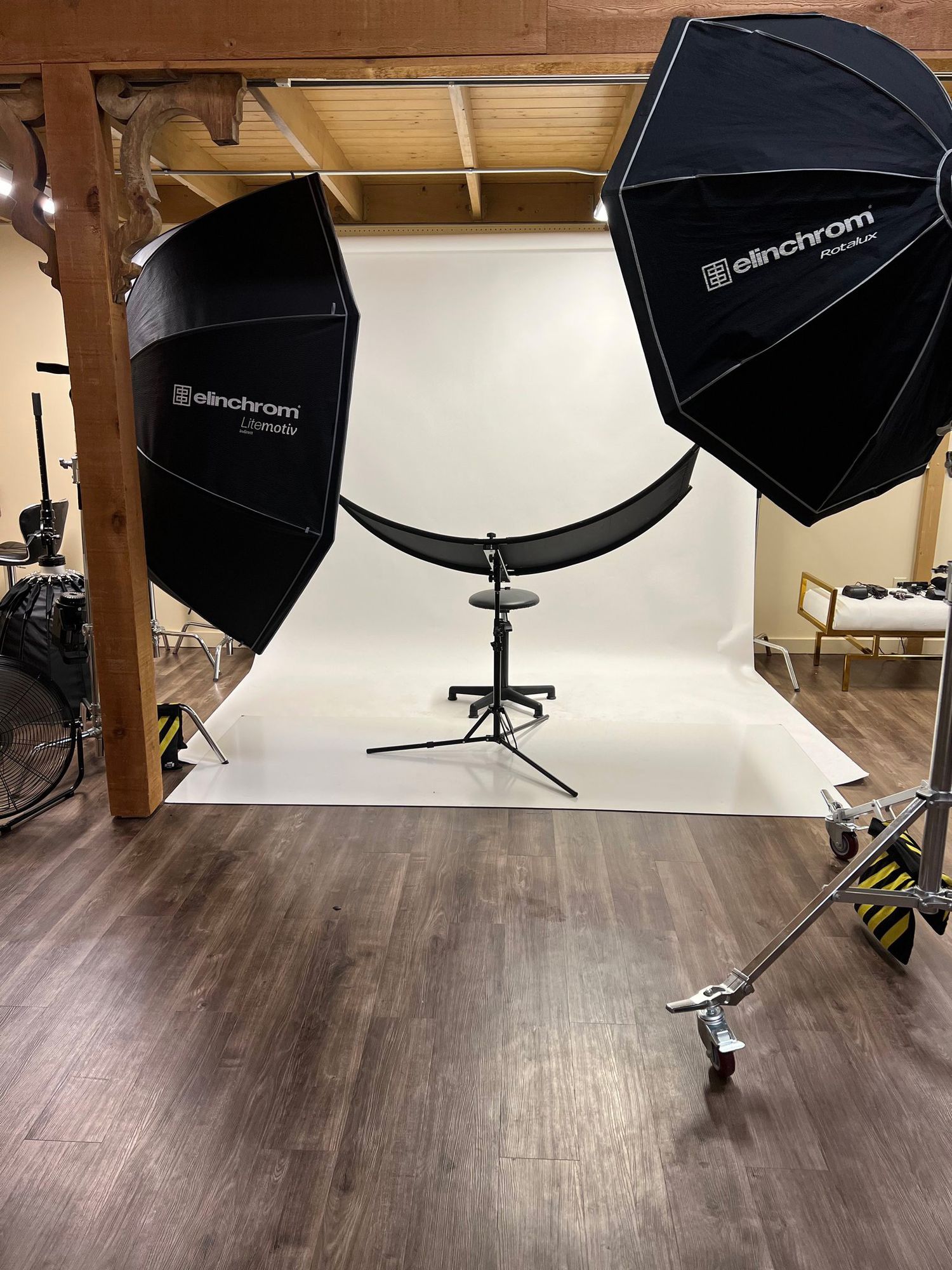 Professional photography studio setup with white backdrop, octagon softboxes, and reflector on wooden floor.