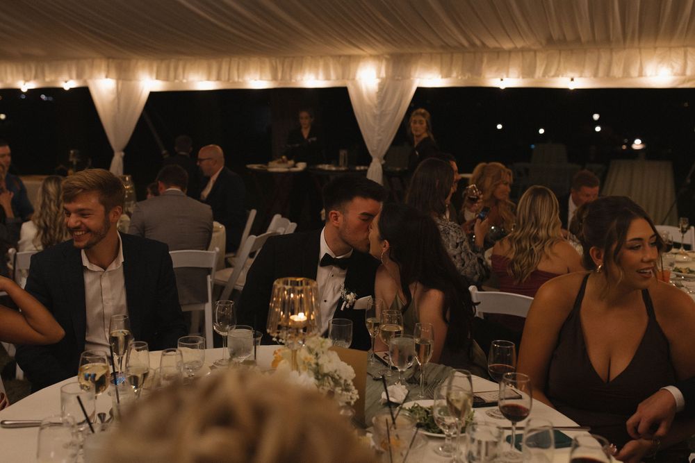 Dimly lit indoor reception venue with elegant table settings and glassware.