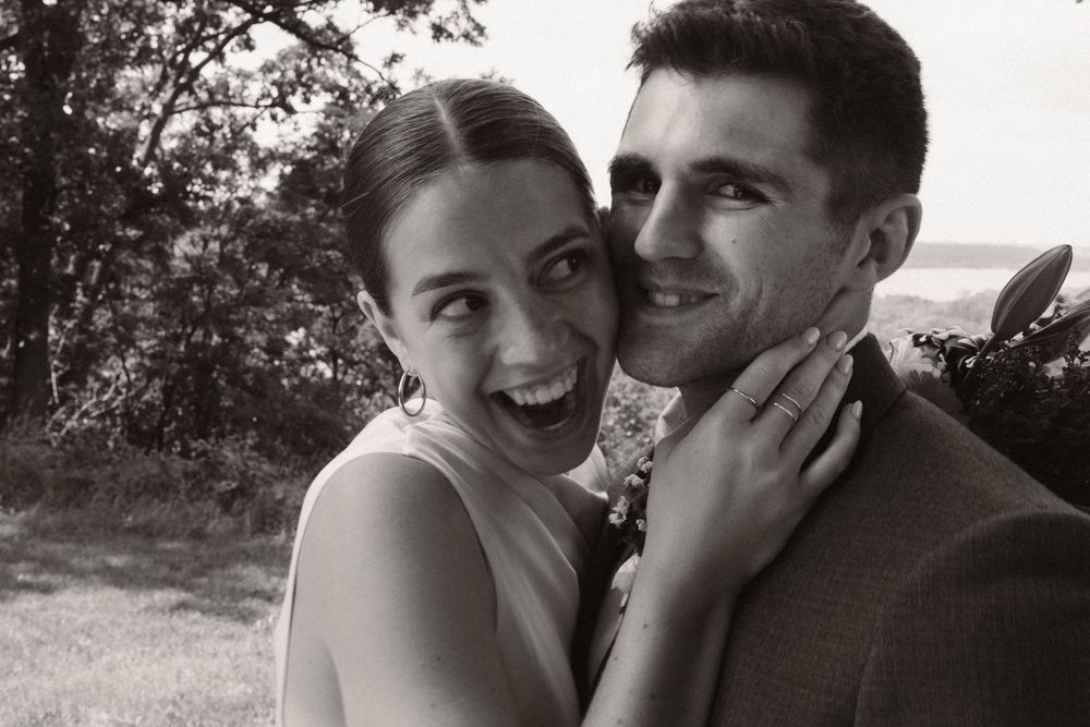 A black and white close-up of a couple sharing a joyful moment outdoors.