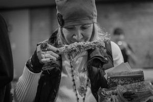 Person in winter hat eating food from a large jar in black and white photography.