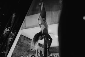 A dynamic aerial performance captured in black and white as the artist hangs upside down from silks.