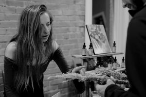 Person reaching across table during social gathering in brick-walled space.