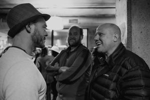 Three people engaged in animated conversation in casual indoor setting.