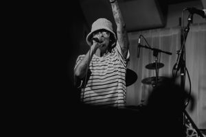 A black and white portrait of a musician performing with a microphone in a bucket hat.