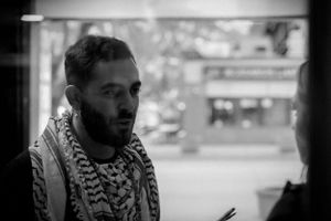 A person wearing a patterned scarf engaged in conversation against a blurred background.