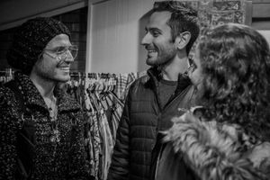 Three people engaged in casual conversation inside what appears to be a clothing store.