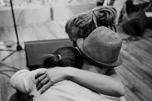 Two people share an emotional embrace during what appears to be a concert or performance.