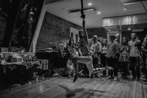 A wide shot of an aerial performance space with audience members gathered around watching the show.