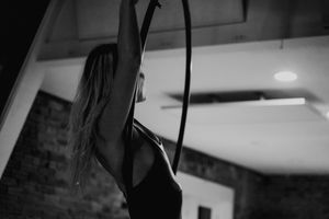 A black and white capture of an aerial performer gracefully posing on a suspended hoop.