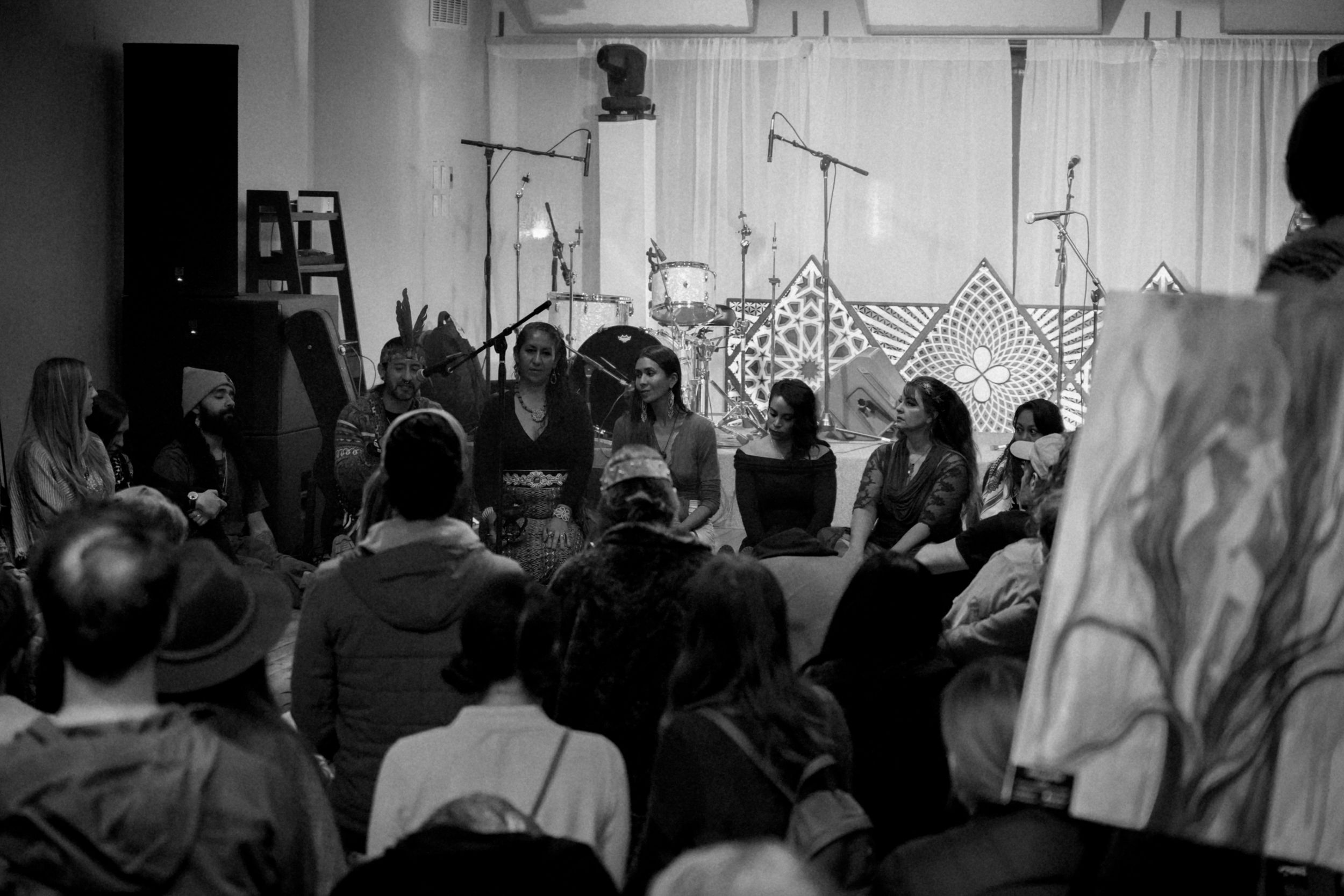 A crowded room of seated attendees watching a performance or presentation in monochrome.