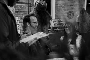 People gathered in casual social setting with exposed brick walls and ambient lighting.