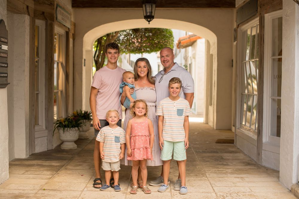 Family walking through a bright Mediterranean style covered walkway with white columns and tiled floors.