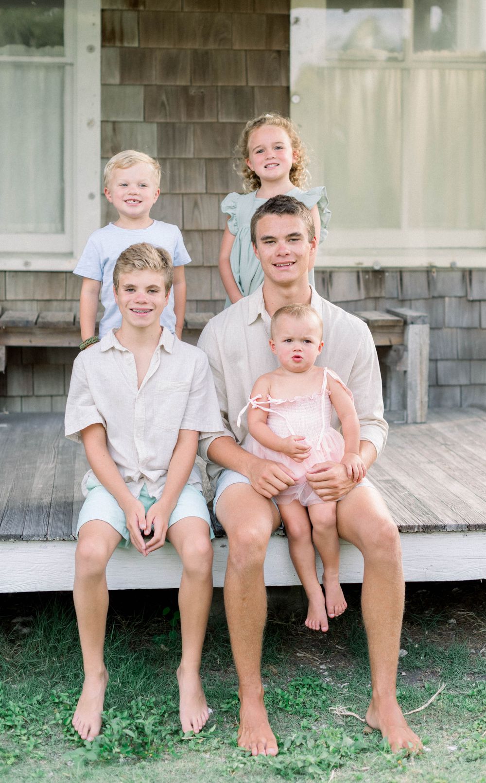 Family members sitting together on a wooden porch in casual summer clothing.