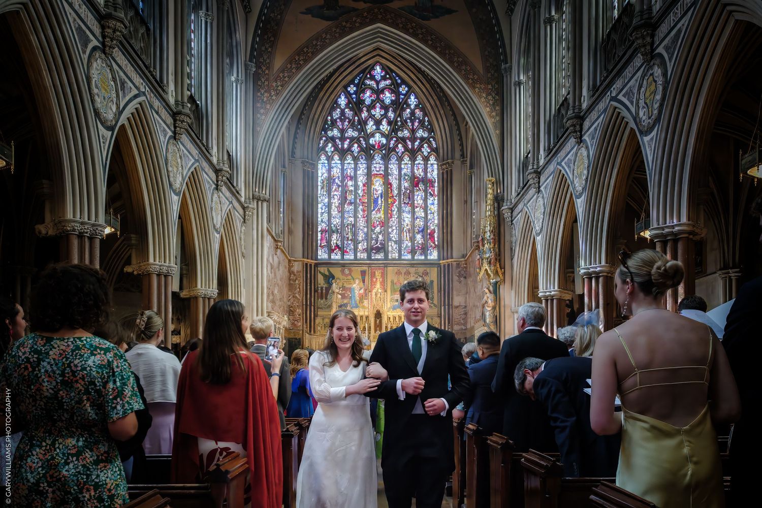 Wedding couple exits church ceremony while guests throw confetti and petals in celebration at traditional ceremony.