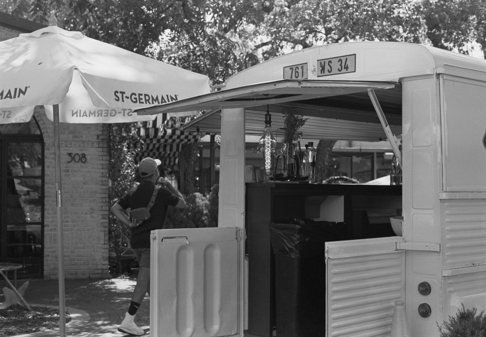A collage of mobile food and retail trailers lined up at an outdoor event venue in black and white.