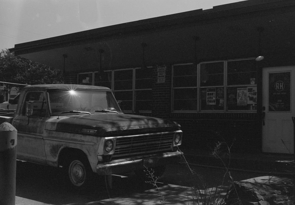 A vintage Ford pickup truck parked outside a building at night with illuminated exterior lighting.