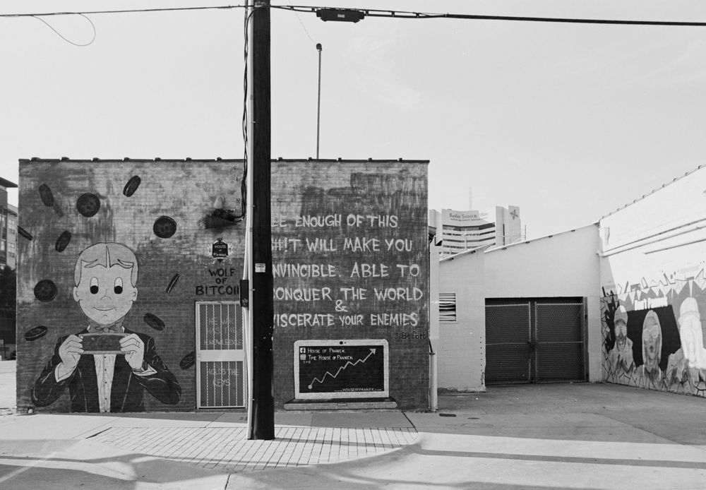 Black and white photographs of graffiti art and murals on concrete walls along an urban street.