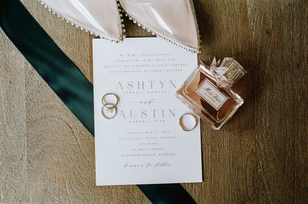 Close-up view of invitation cards and vintage perfume bottles arranged artistically on a textured surface.