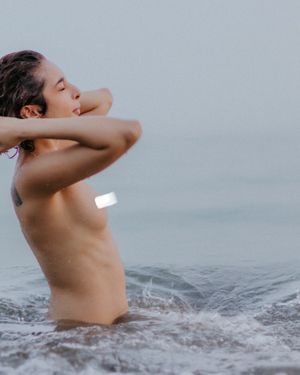 Artistic black and white photo of a person swimming in moody ocean waters during an overcast day.