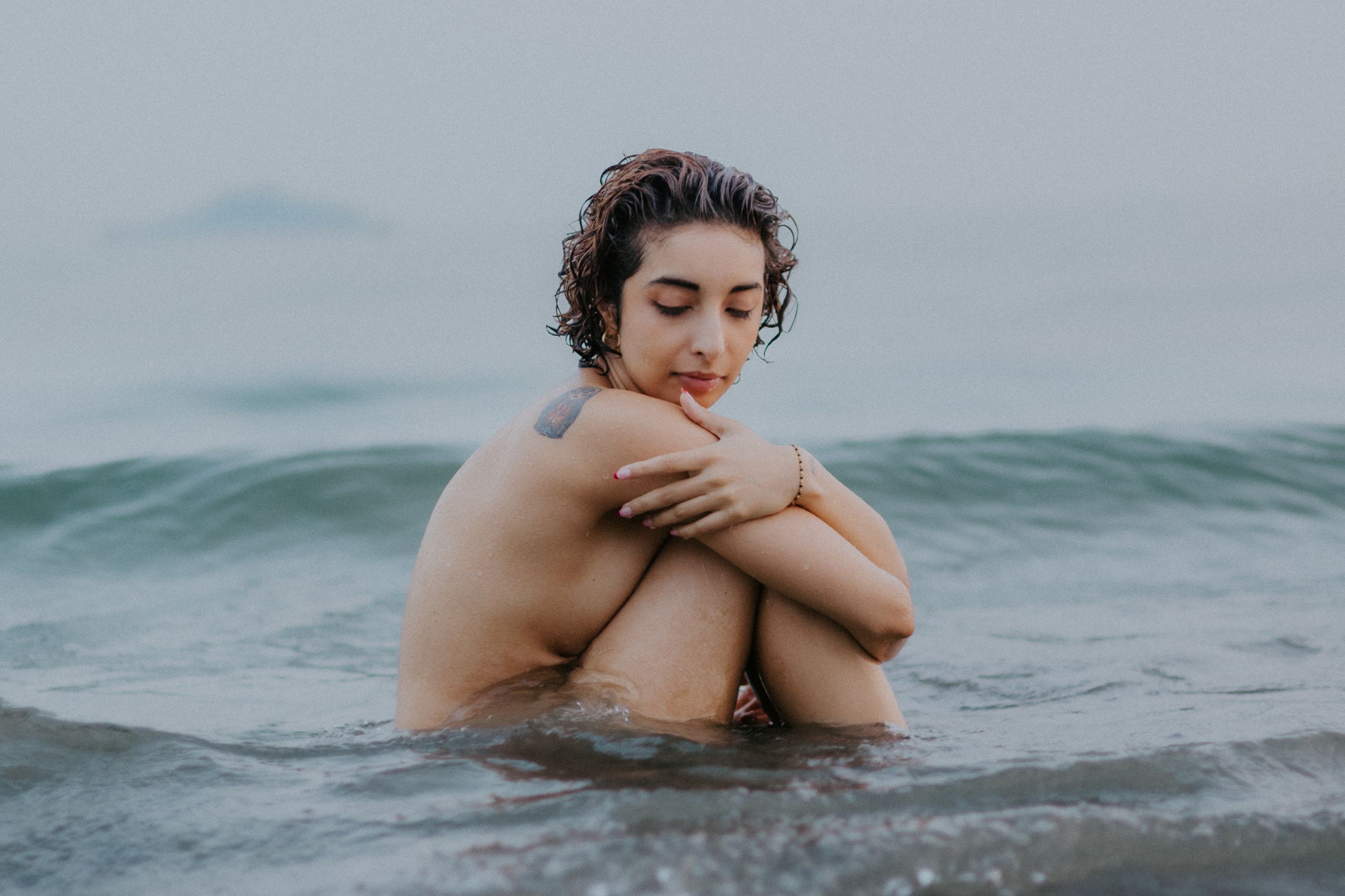 Artistic portrait in ocean waves showing vulnerability and self-reflection.