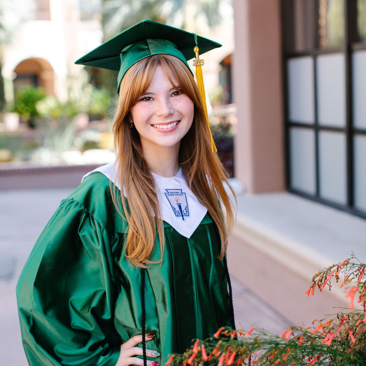 Smiling graduate wearing a green cap and gown