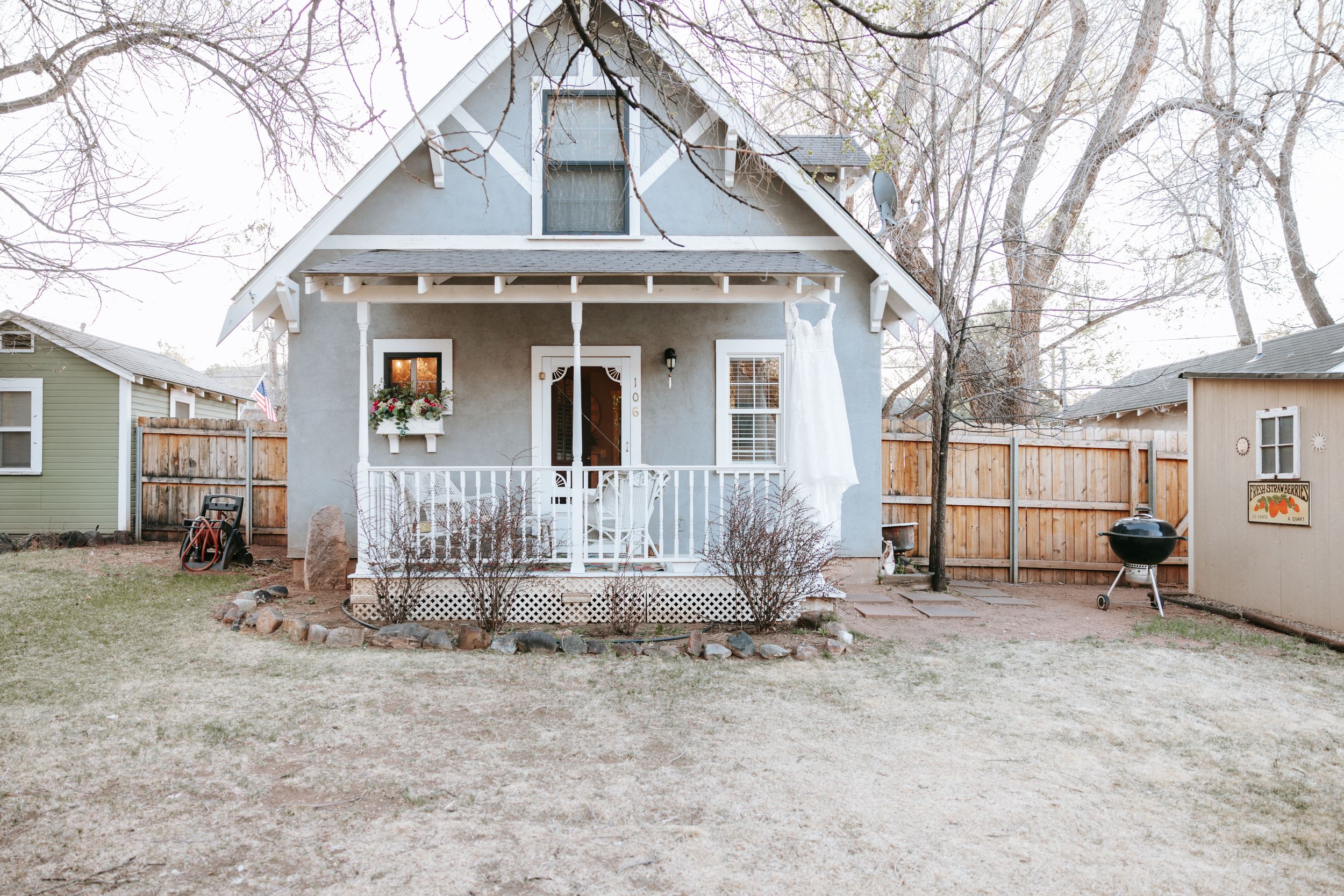 A charming blue cottage-style house with a white porch and bare trees in winter.