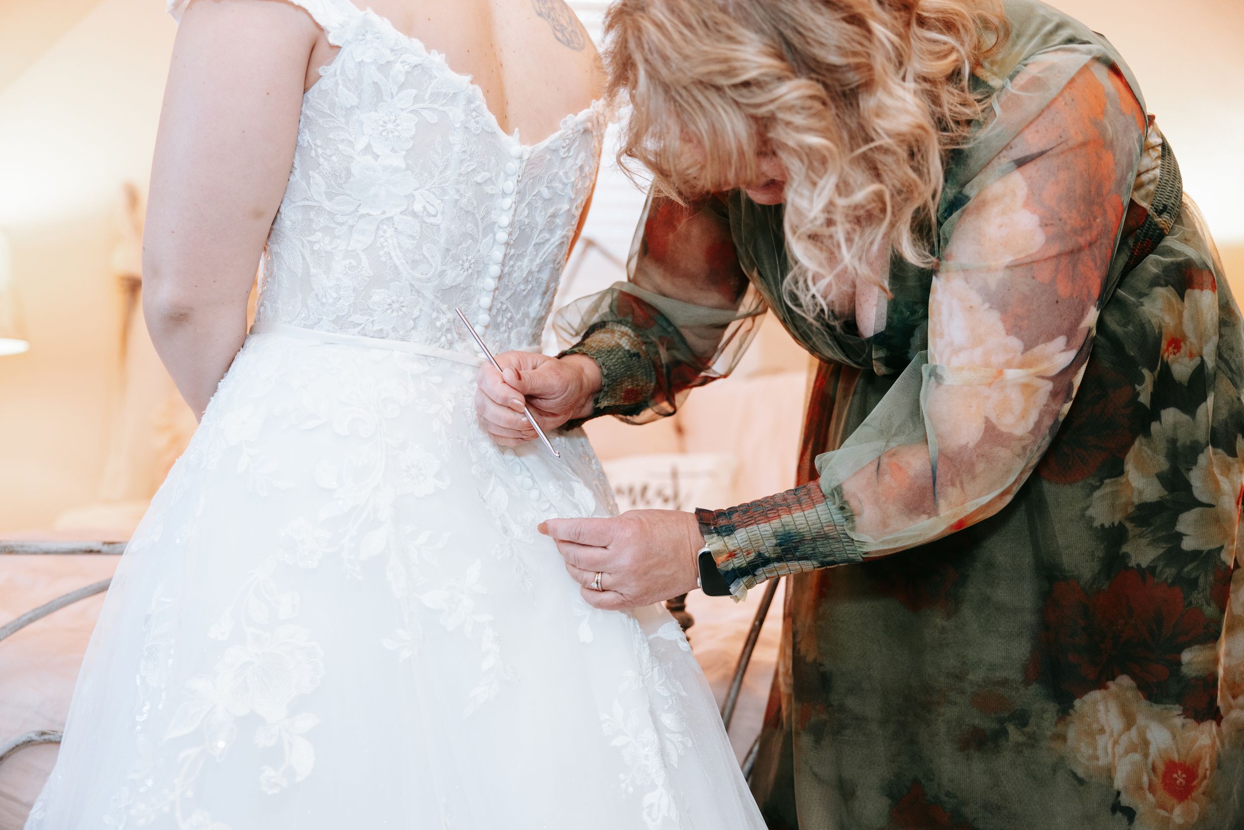 Two hands performing handfasting ritual with white and green ribbons during wedding ceremony.
