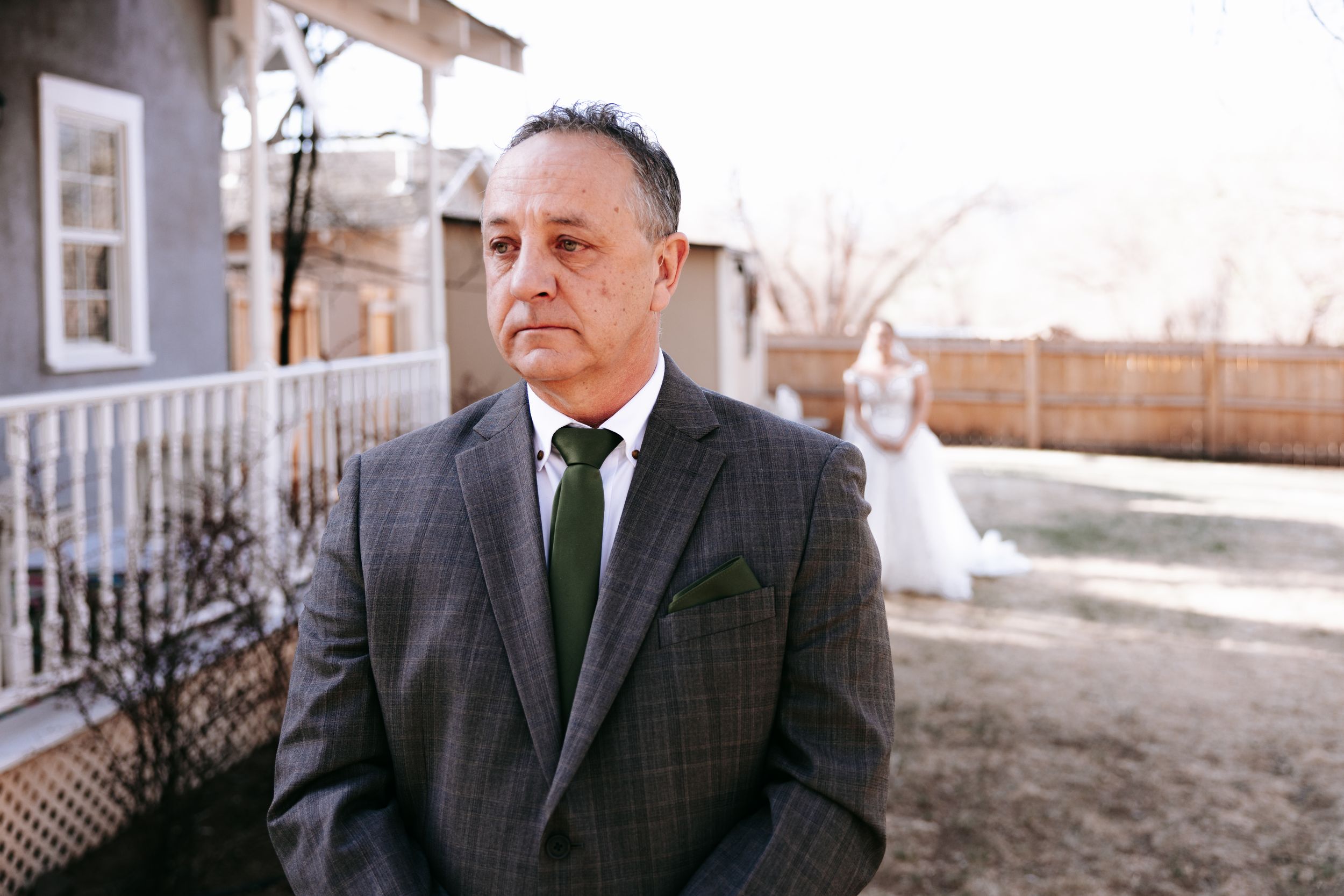 Groomsmen in dark suits standing outside traditional building.