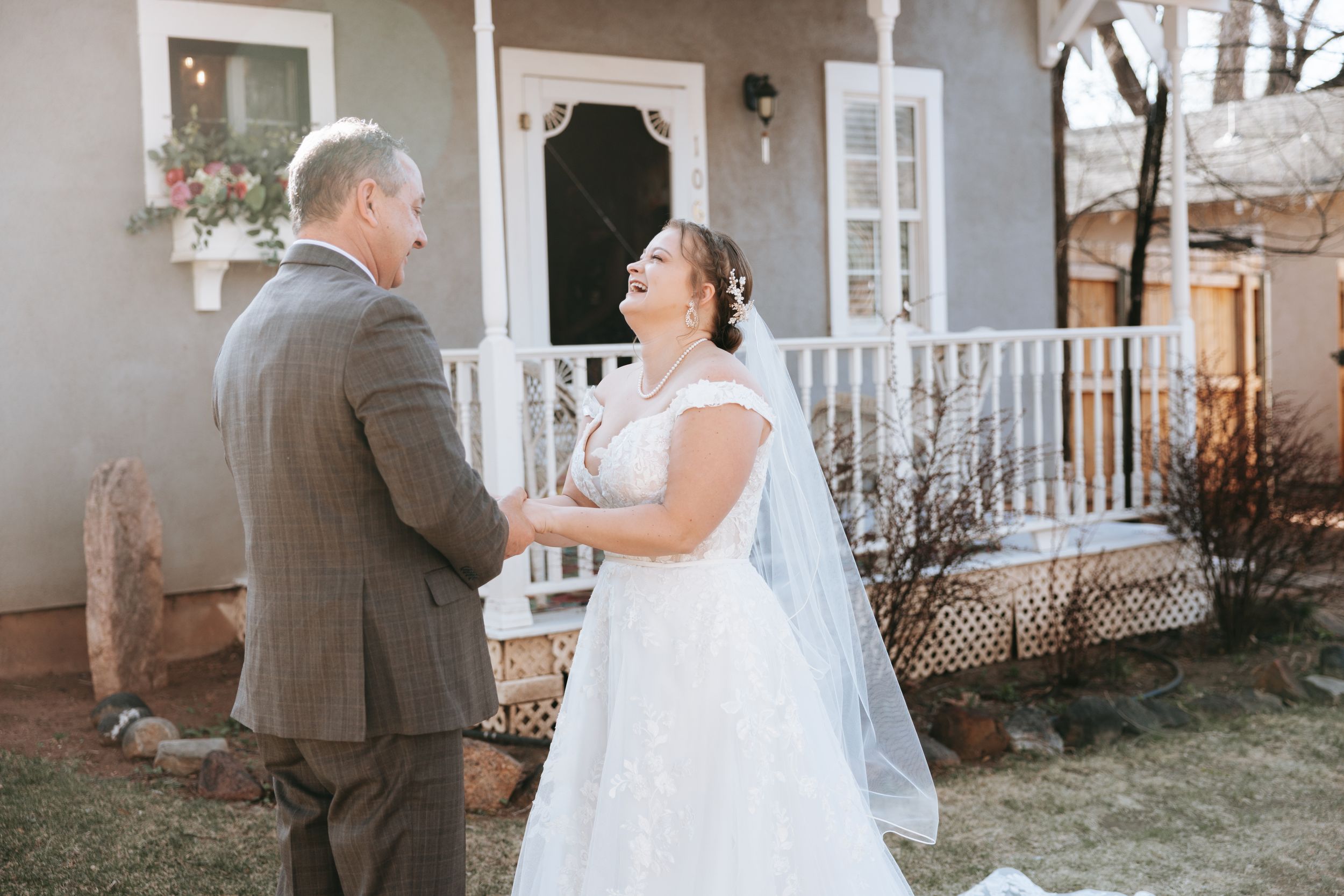 A wedding day moment captured between a couple on a front porch of a charming house.