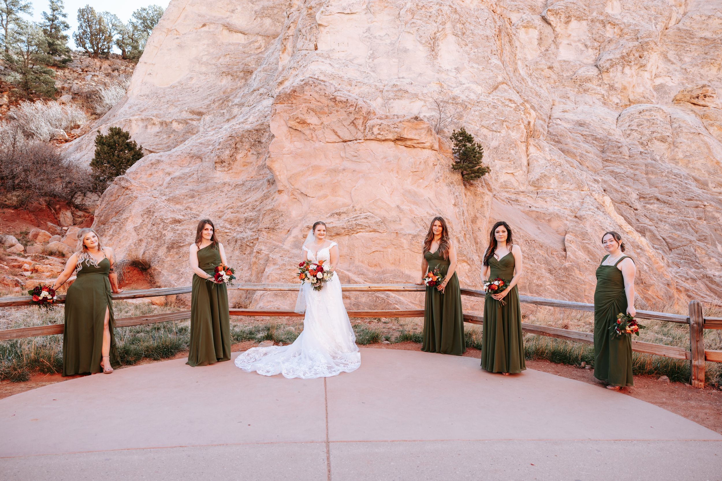 Wedding party poses against red rock formations in desert landscape.