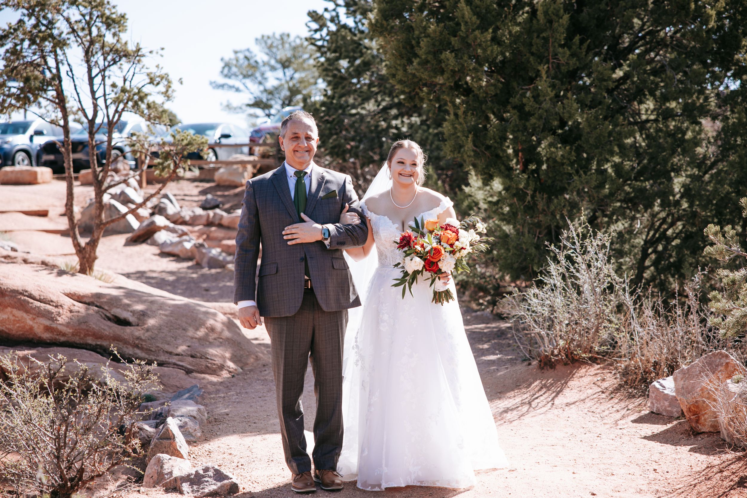 Couple takes wedding photos in a scenic desert landscape with rocky terrain.