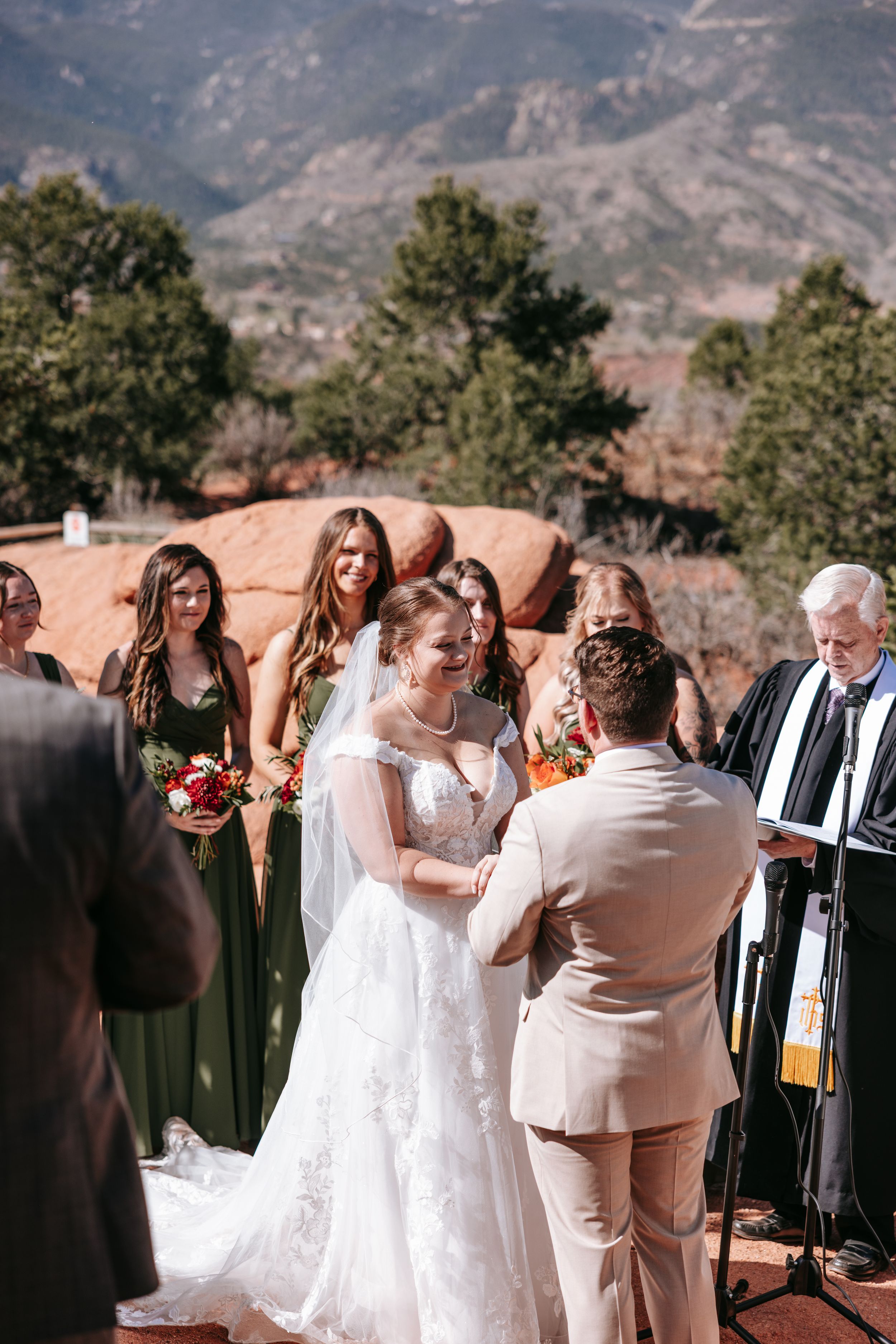 A wedding ceremony taking place outdoors at Garden of the Gods with mountain vistas and red rocks in the background.