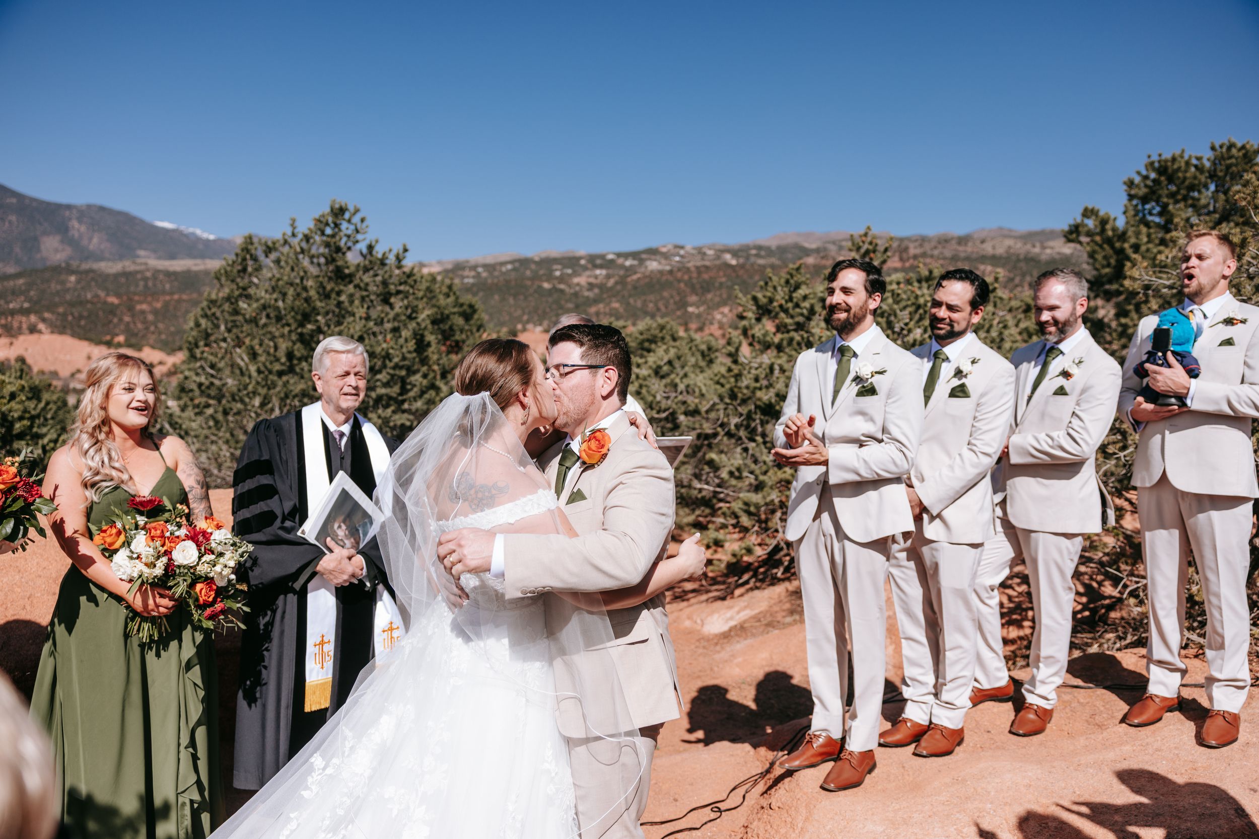 An outdoor wedding ceremony takes place on a scenic mountain overlook on a bright sunny day.