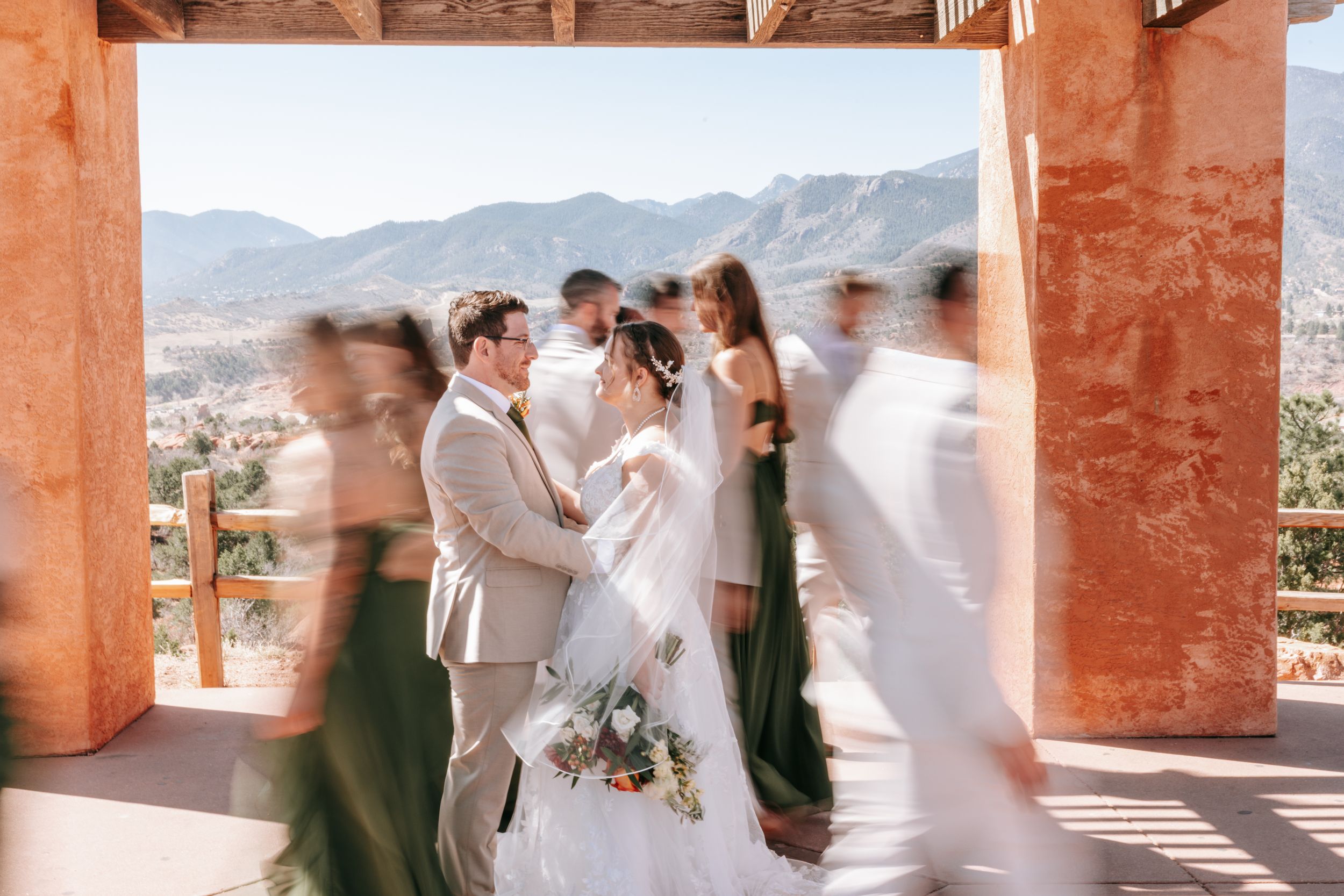 Wedding celebration captured in an outdoor venue with terracotta walls and mountain views in background.