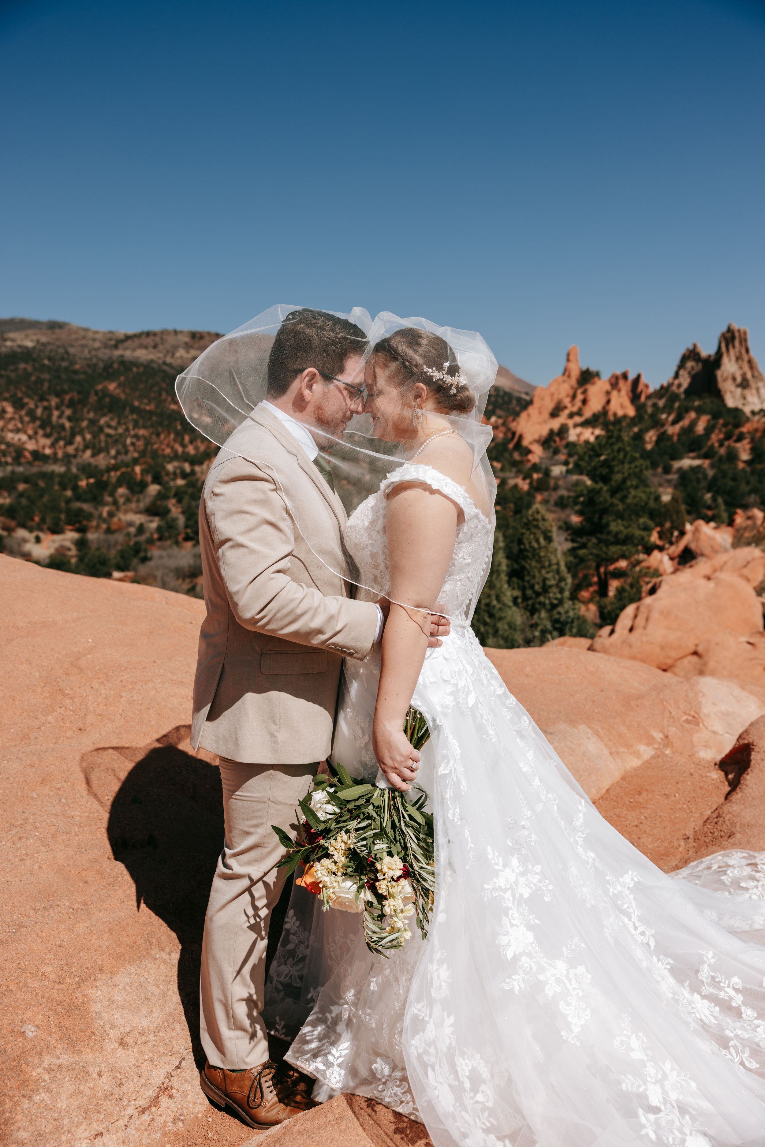 Romantic wedding couple embraces in front of stunning red rock formations at Garden of the Gods in Colorado.