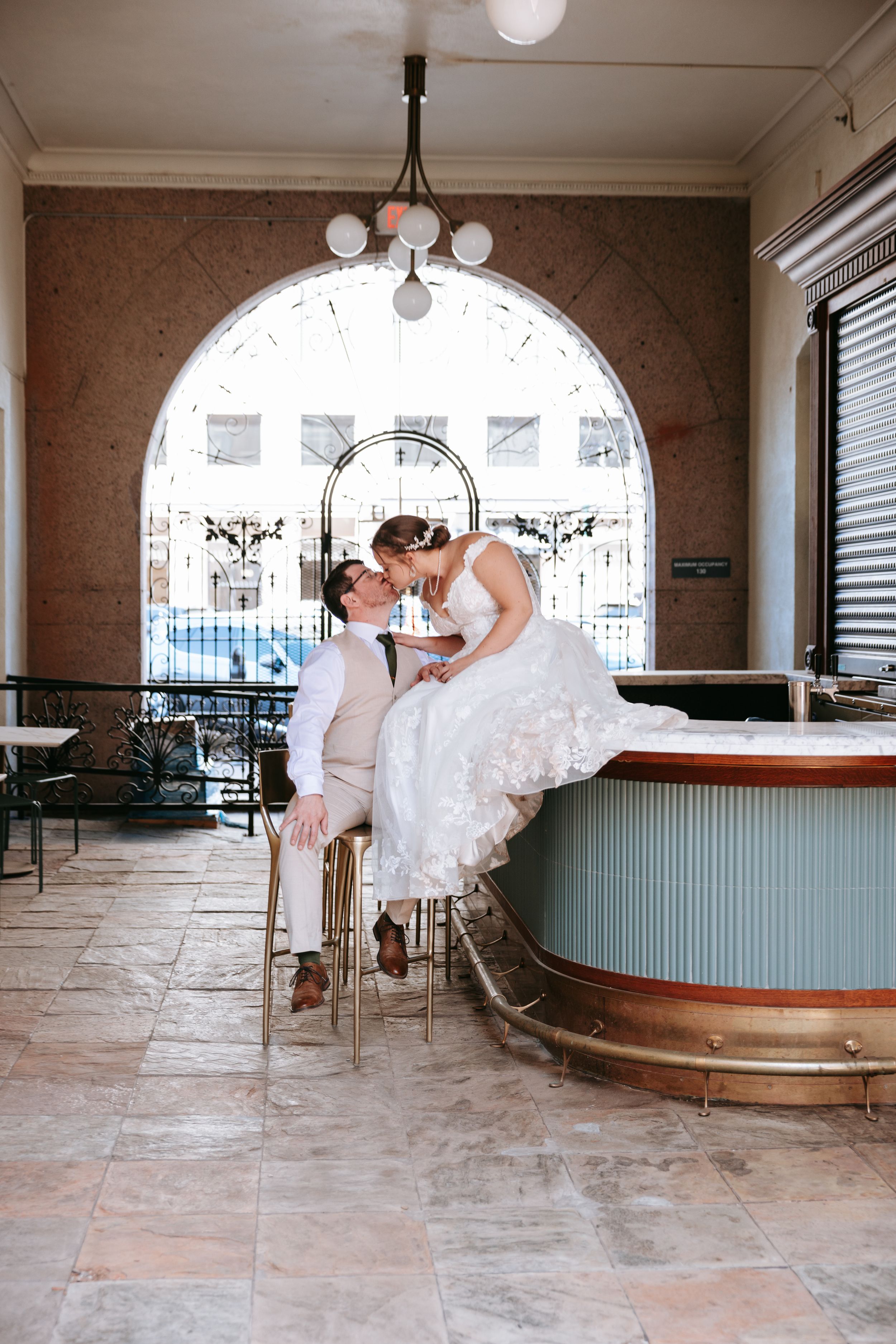 A person in a white wedding dress twirls on a tiled floor in an elegant indoor venue.