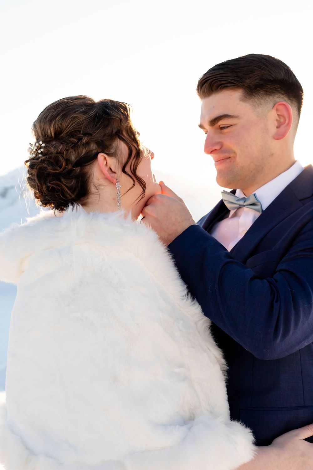 Series of romantic embrace shots between couple wearing white fluffy dress and navy suit during a wedding.