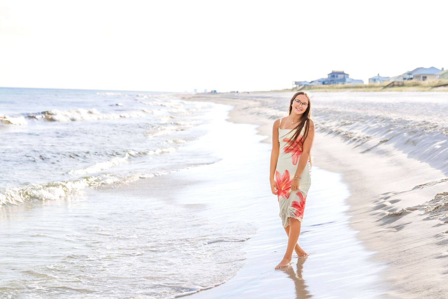 Woman in red swimsuit running joyfully through shallow ocean waves on a sunny beach.