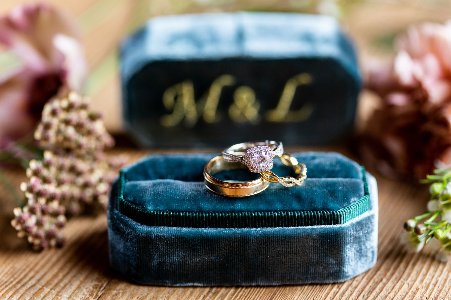 Wedding rings displayed on a dark blue velvet ring box with floral decorations.