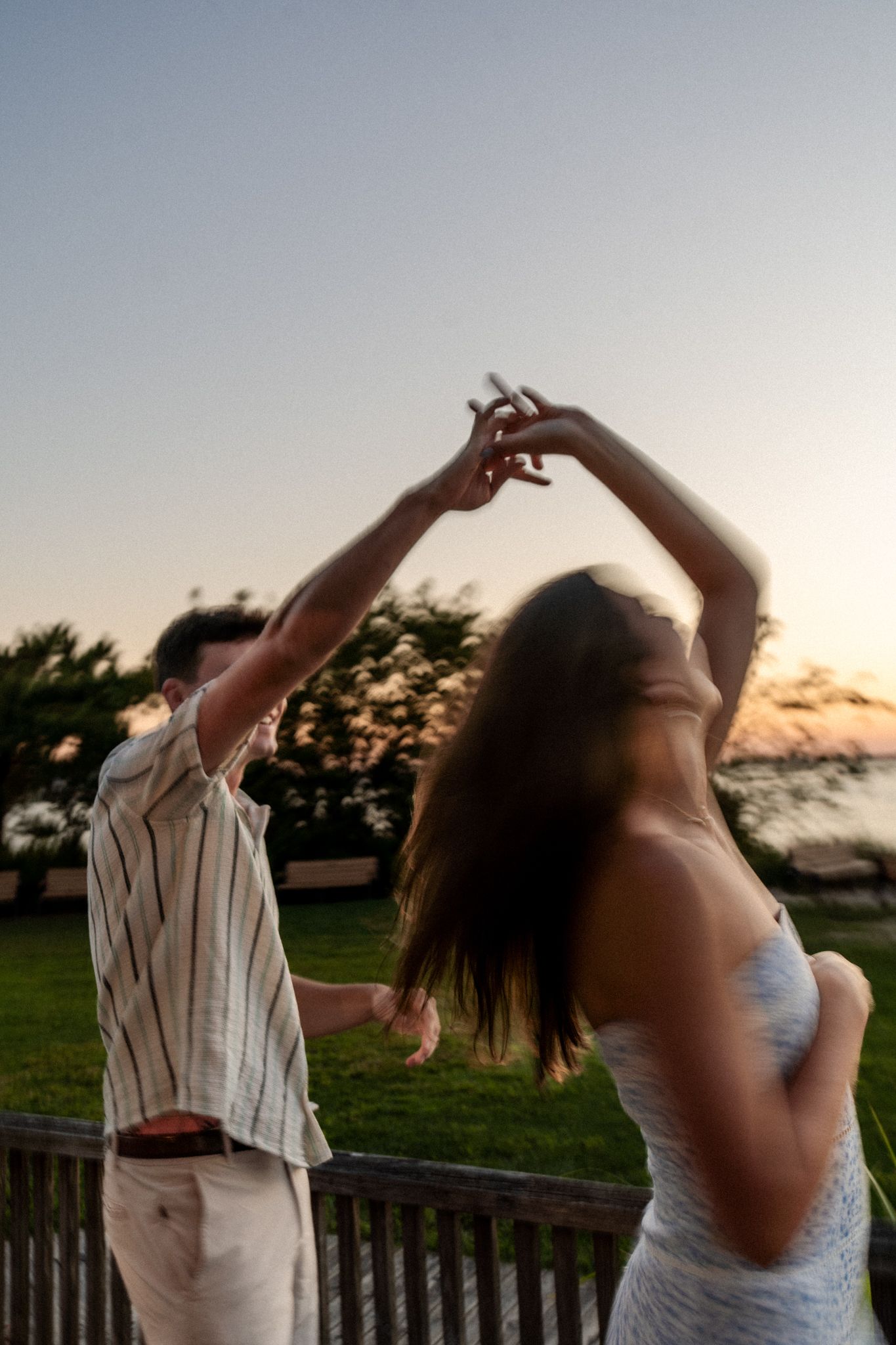 A couple dancing together during sunset on a beachfront deck.