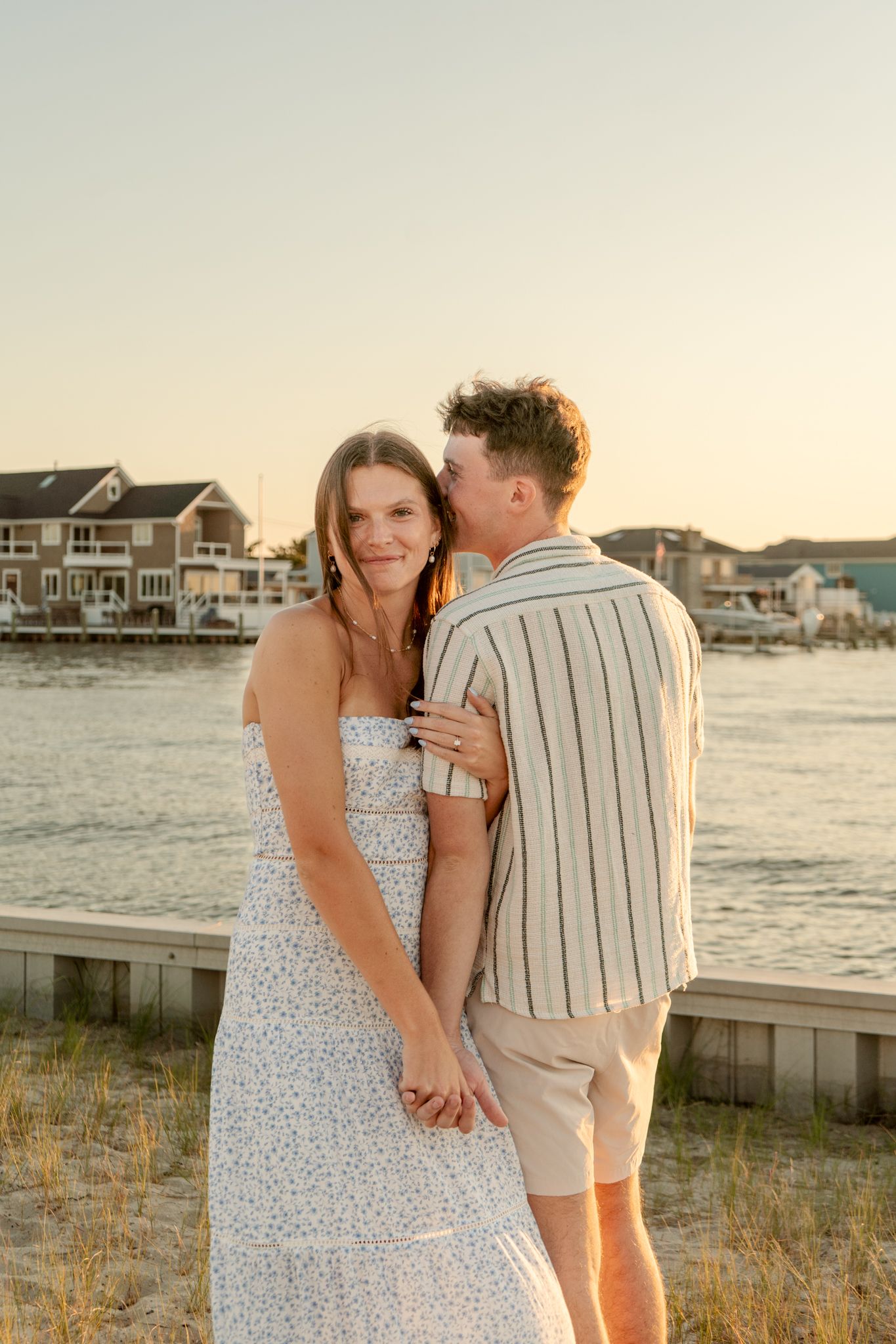 A romantic moment shared between a couple on a coastal boardwalk at sunset.