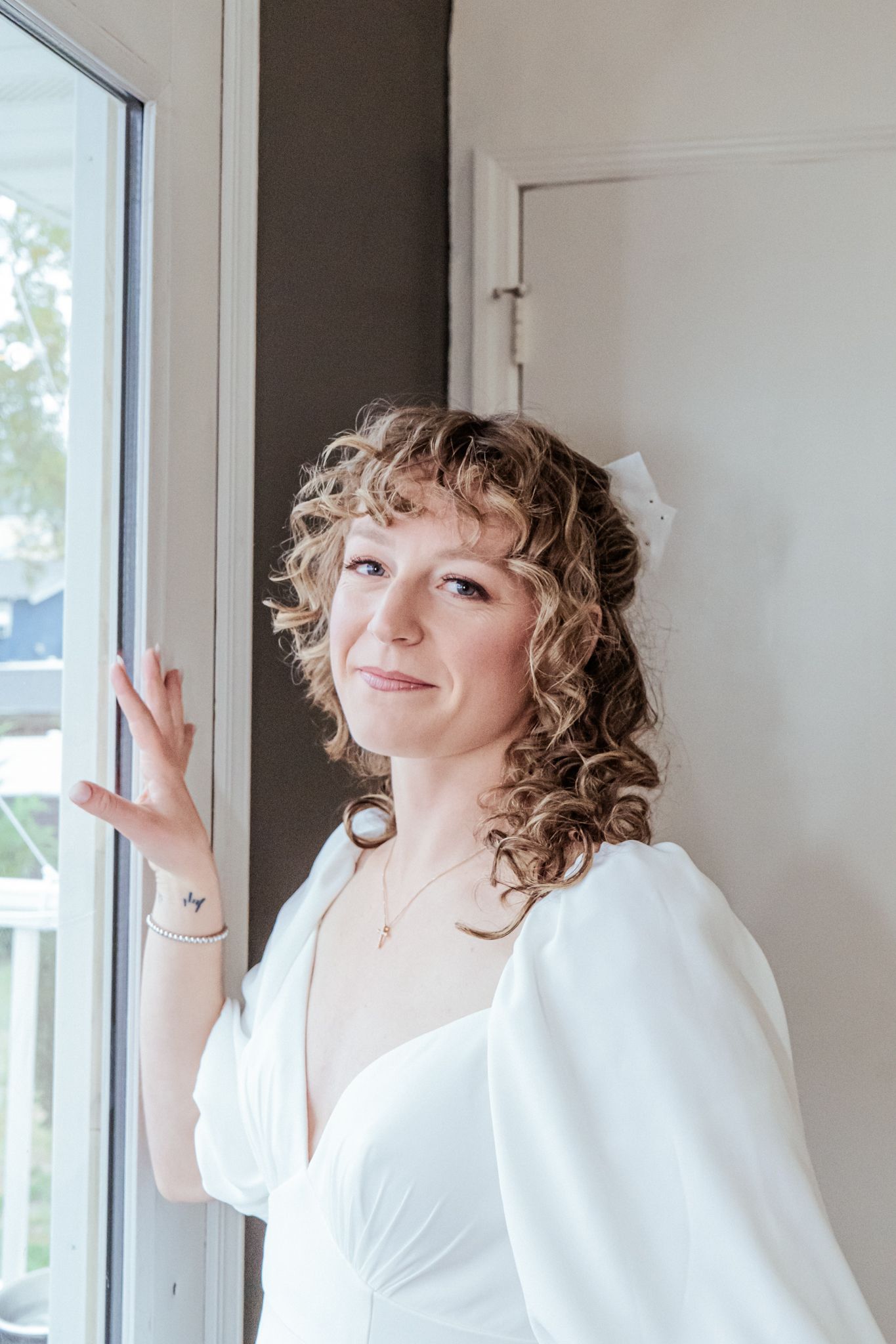 A sequence showing joyful poses in a white robe near bright windows.
