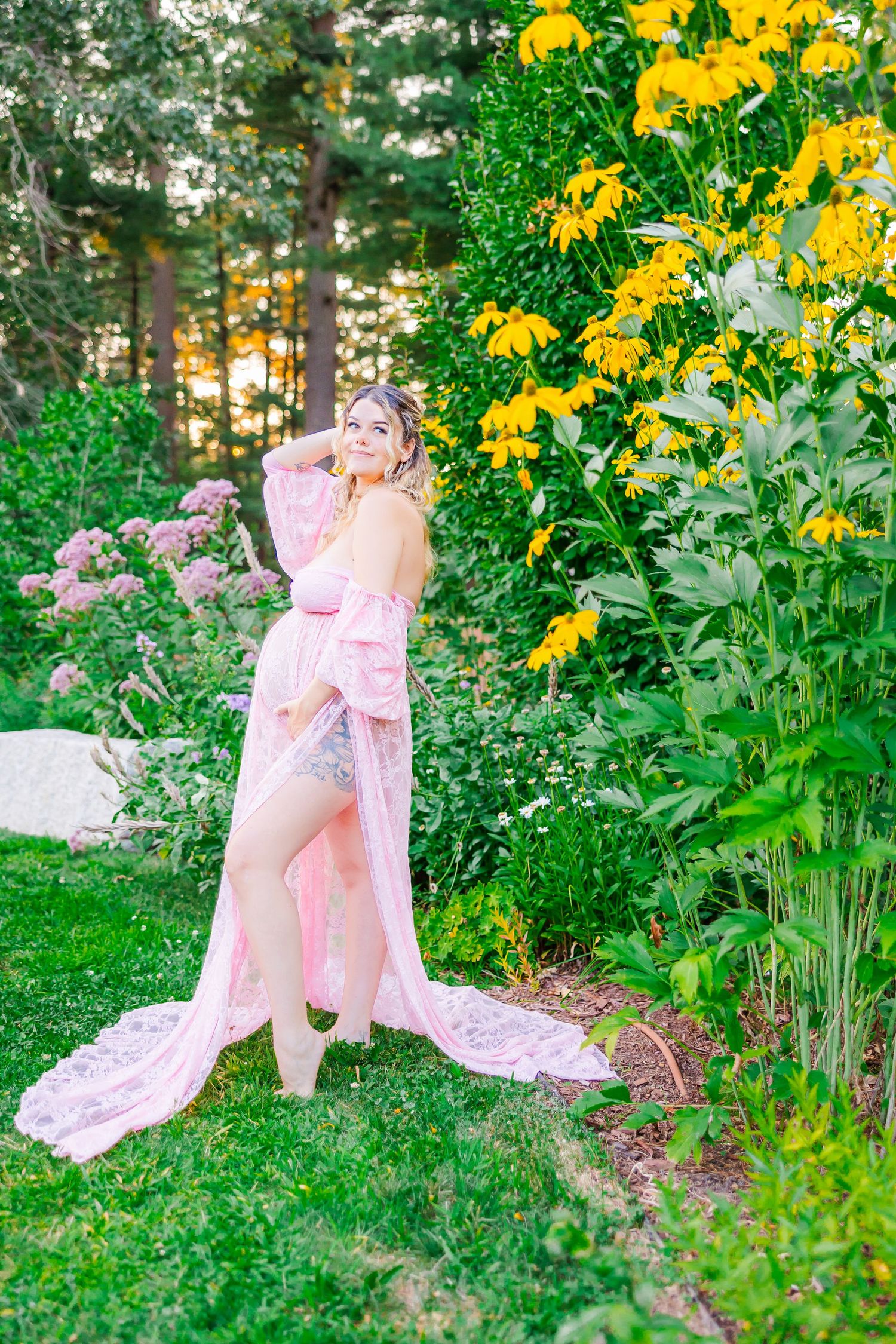 Pink floral gown flows gracefully in a summer garden with bright yellow flowers and lush greenery in the background.