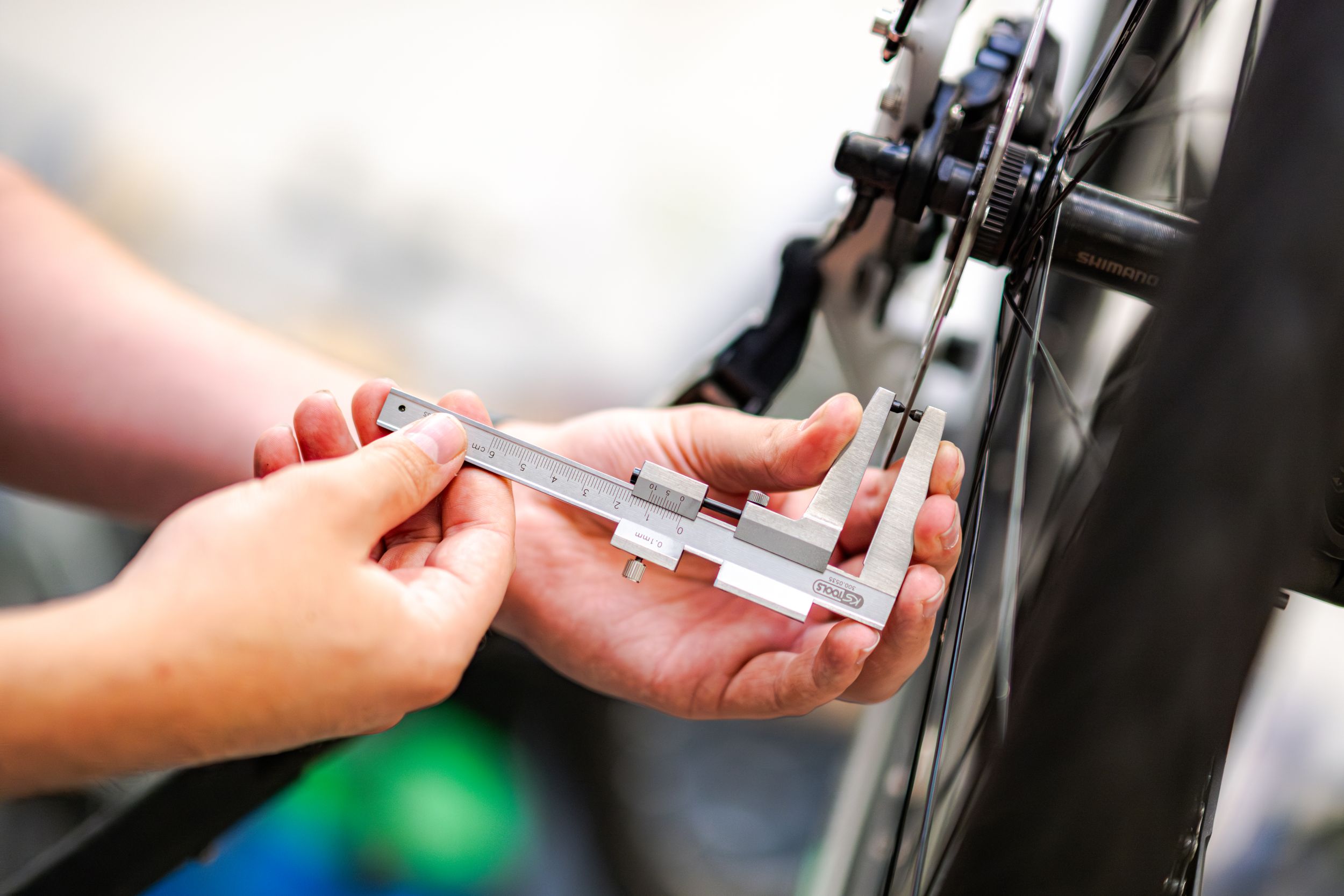 Bicycle mechanic measuring a disc brake rotor.
