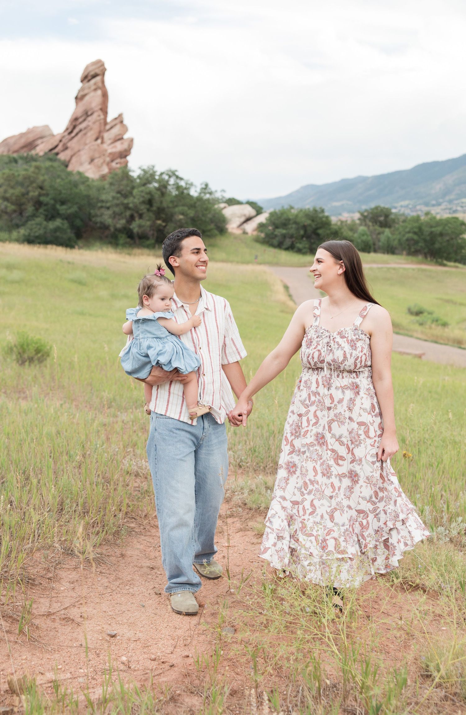 Family enjoying time together in a wildflower meadow with red rock formations in the background on a cloudy day.