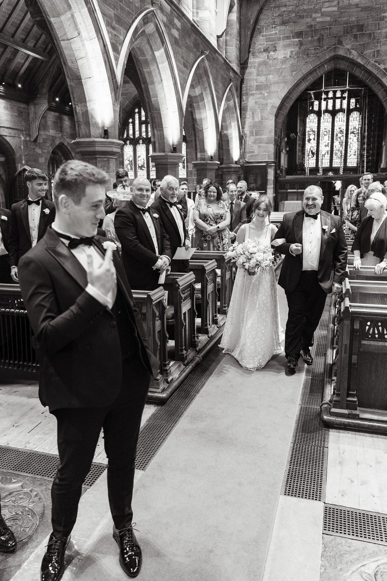 A classic black and white wedding ceremony inside a historic church with elegant gothic arches and stained glass windows.