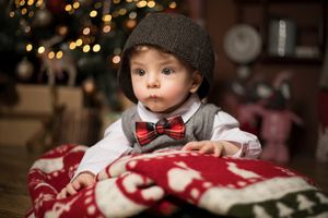 Holiday portrait with dark knit cap and red bow tie against festive holiday bokeh background.